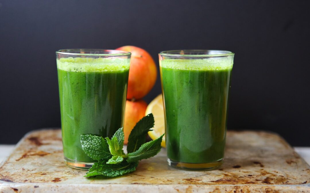 two glasses of green juice with mint, apples and lemon