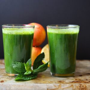 two glasses of green juice with mint, apples and lemon