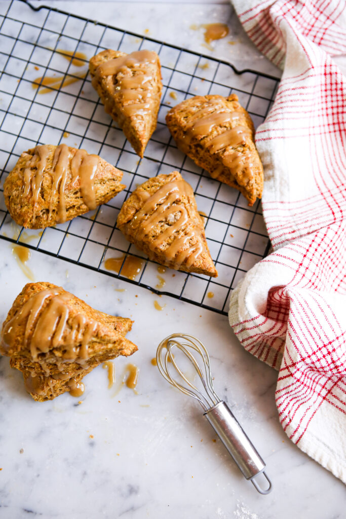 Pumpkin spice scones with maple tahini glaze a whisk and a dish towel