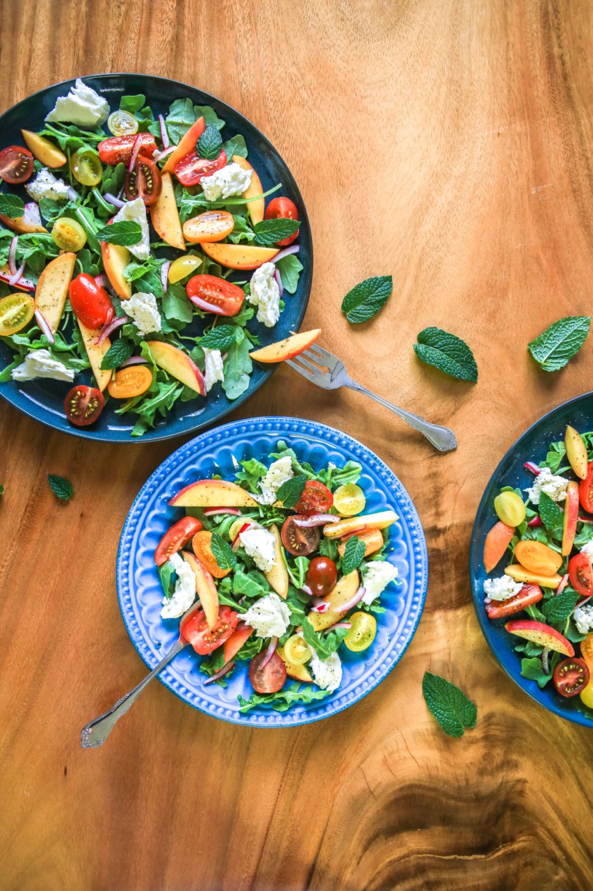 3 plates of salad with peaches, tomatoes, arugula and mint