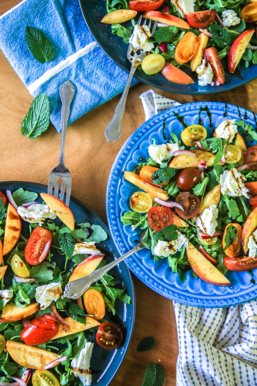 plates of salad with peaches, tomatoes, arugula and mint