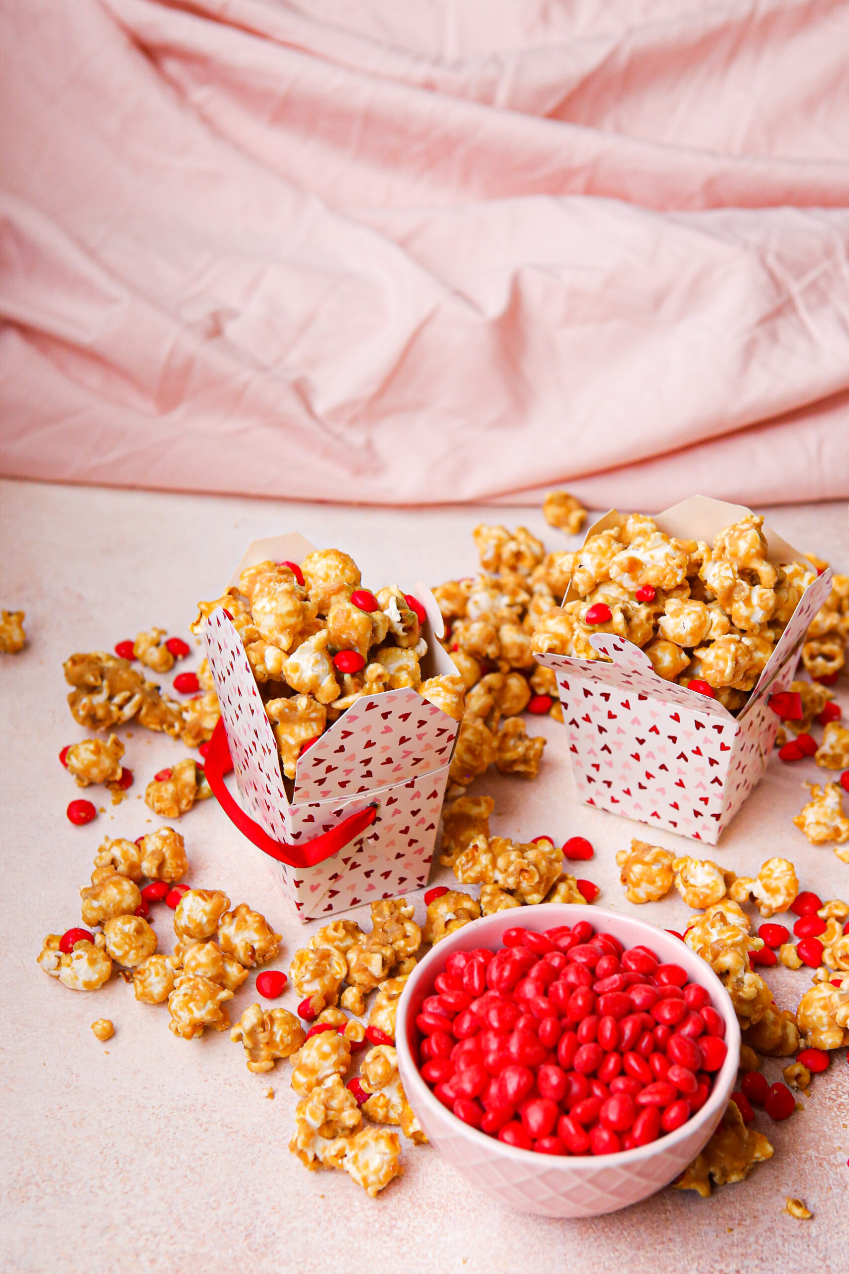 a dish of cinnamon hearts and a couple boxes of caramel corn