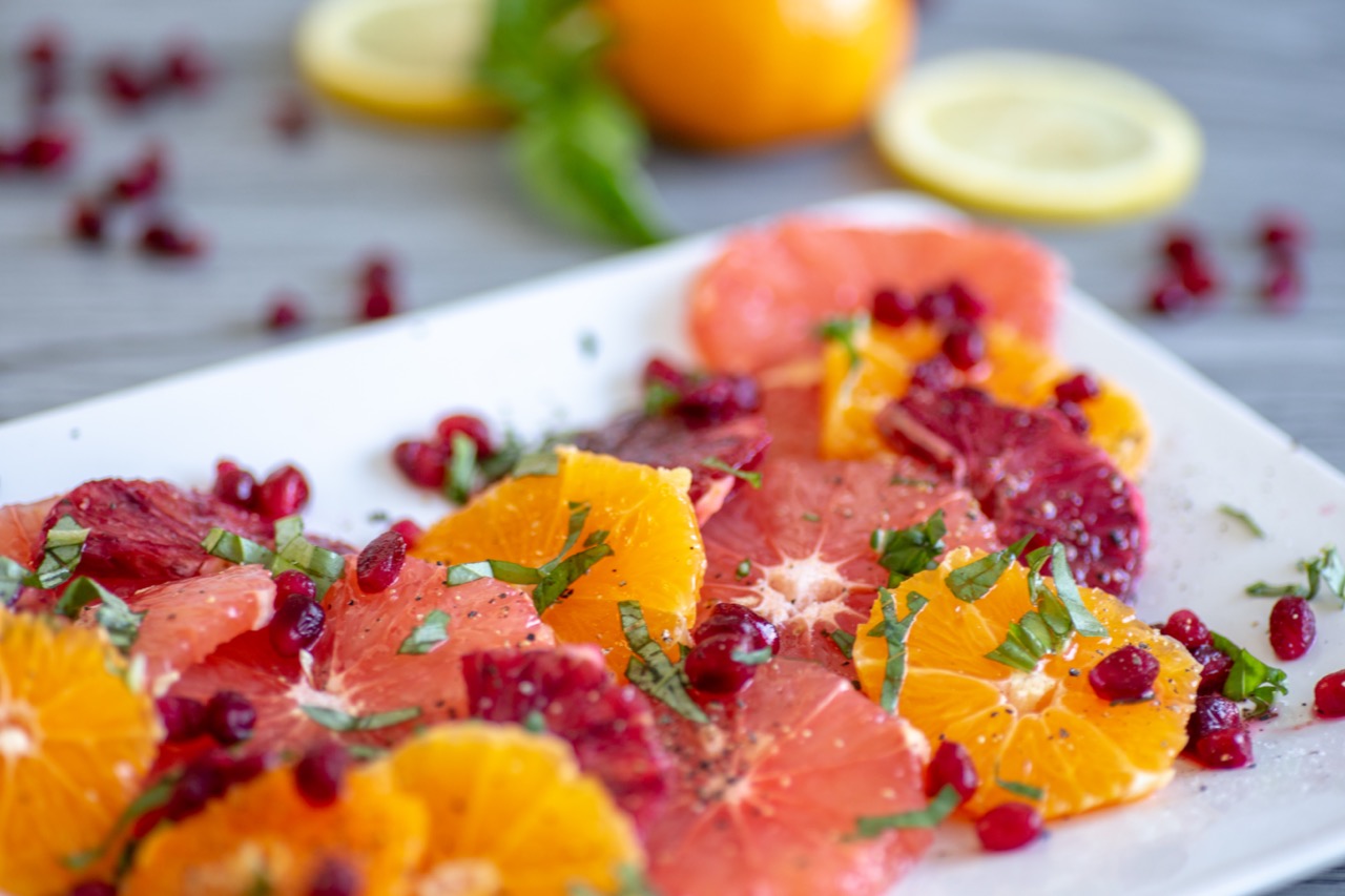 Naval, cara cara and blood oranges on a plate with pomegranate and basil