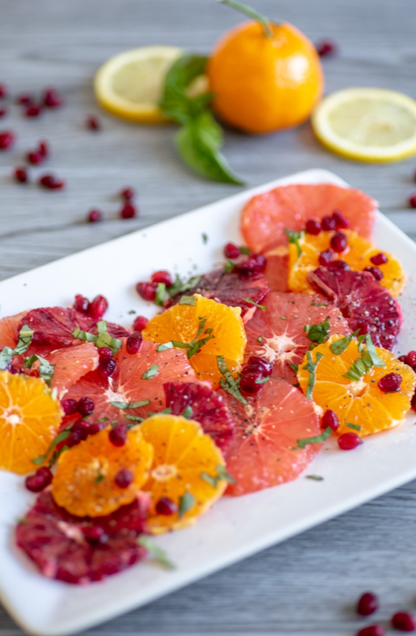 Naval, cara cara and blood oranges on a plate with pomegranate and basil