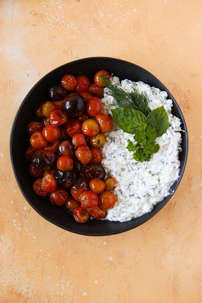 Roasted tomatoes and whipped feta with fresh herbs in a ceramic bowl 