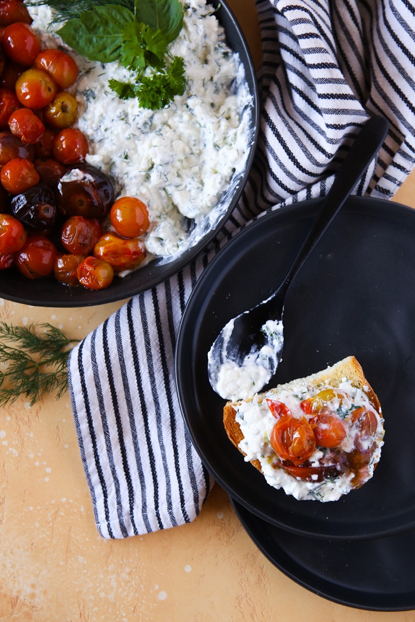 A dish of roasted tomatoes with whipped feta and fresh herbs